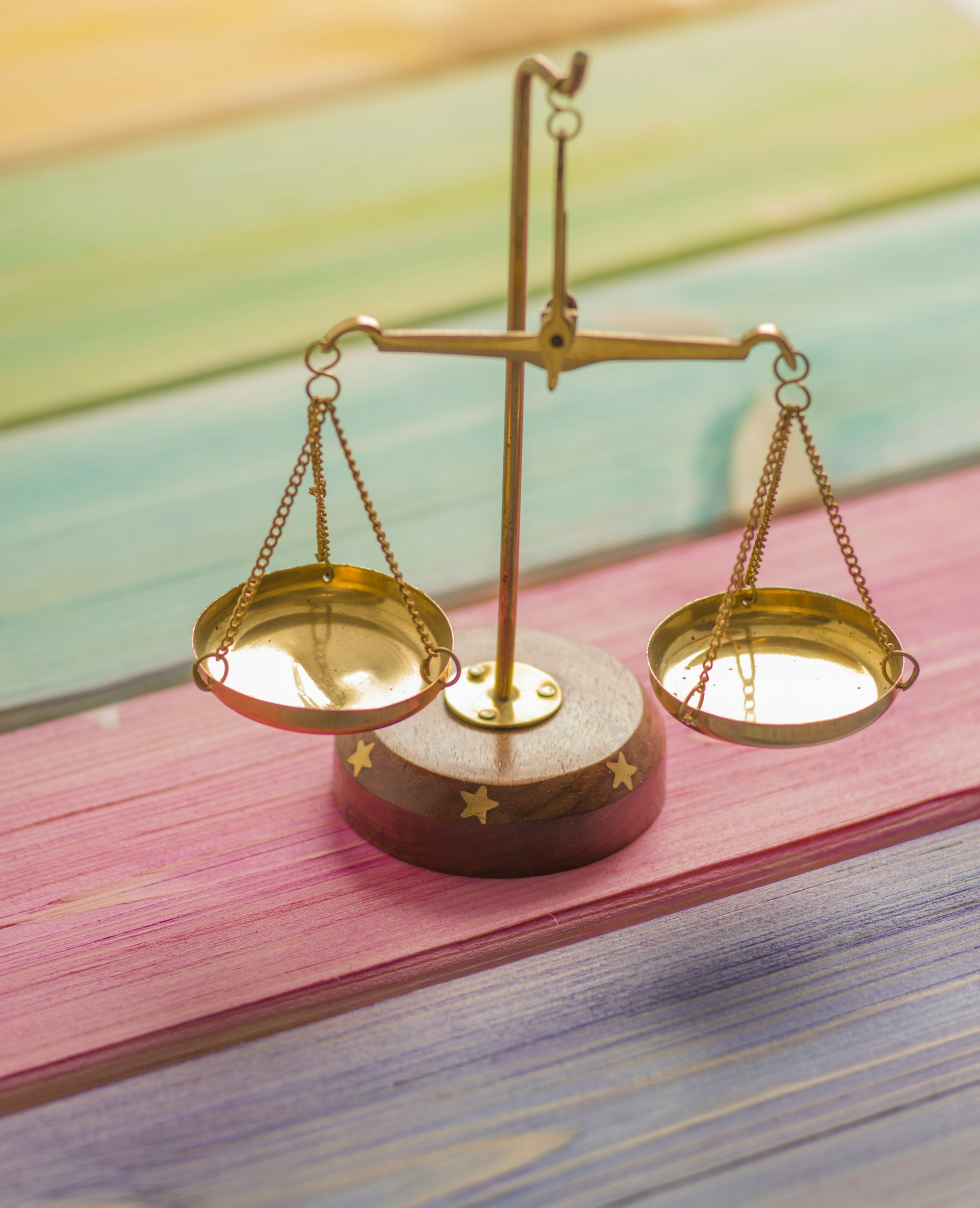 A small brass balance scale resting on a wooden surface