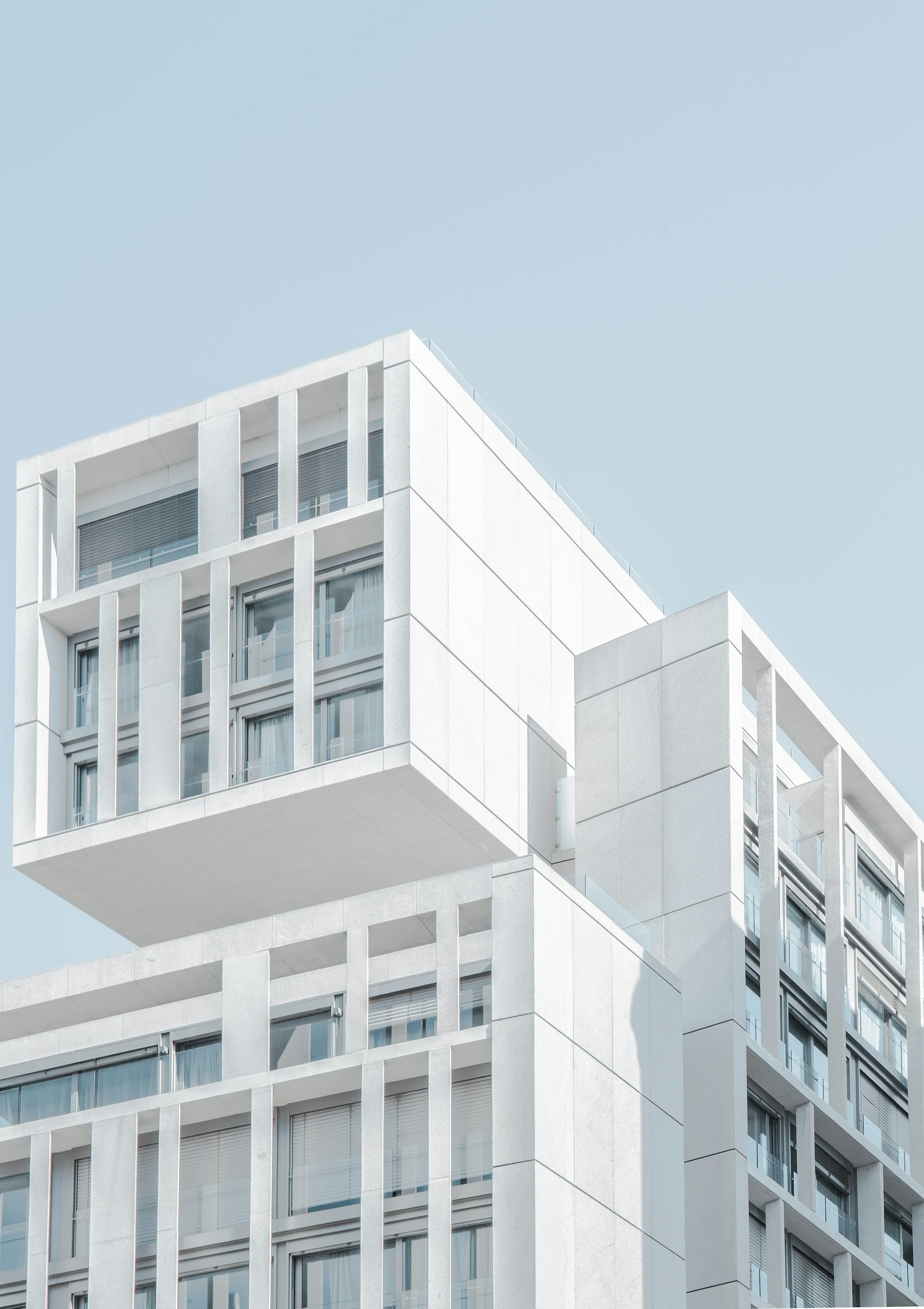 A modern white concrete condo building with cantilevered balconies