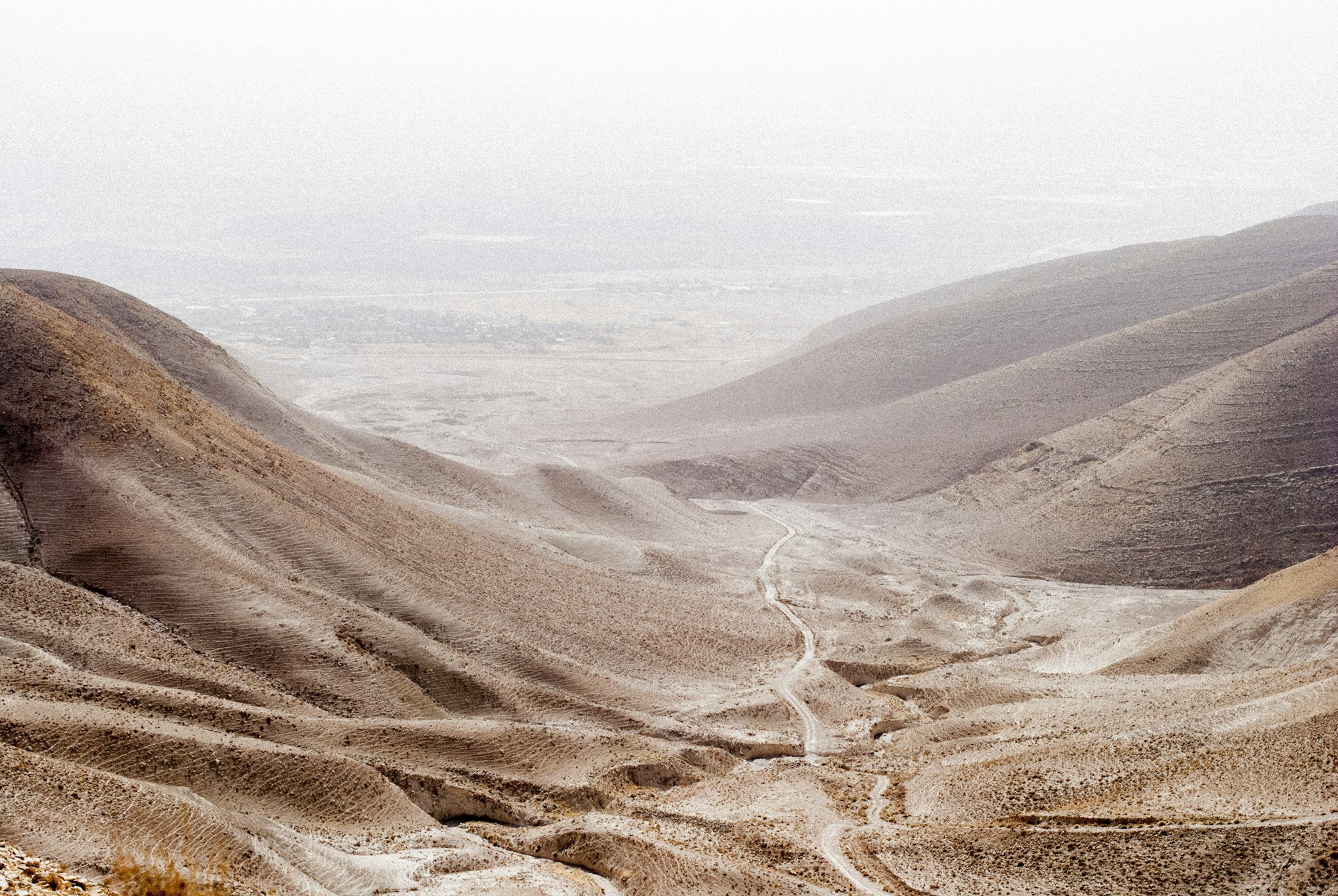 An aerial view of a dirt trail winding through desert hills