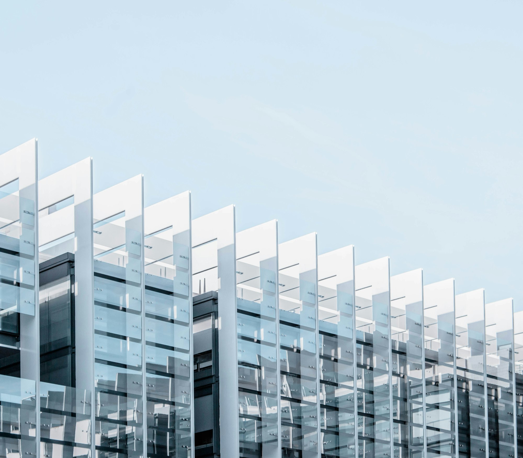 The angular glass facade of a modern office building against a blue sky
