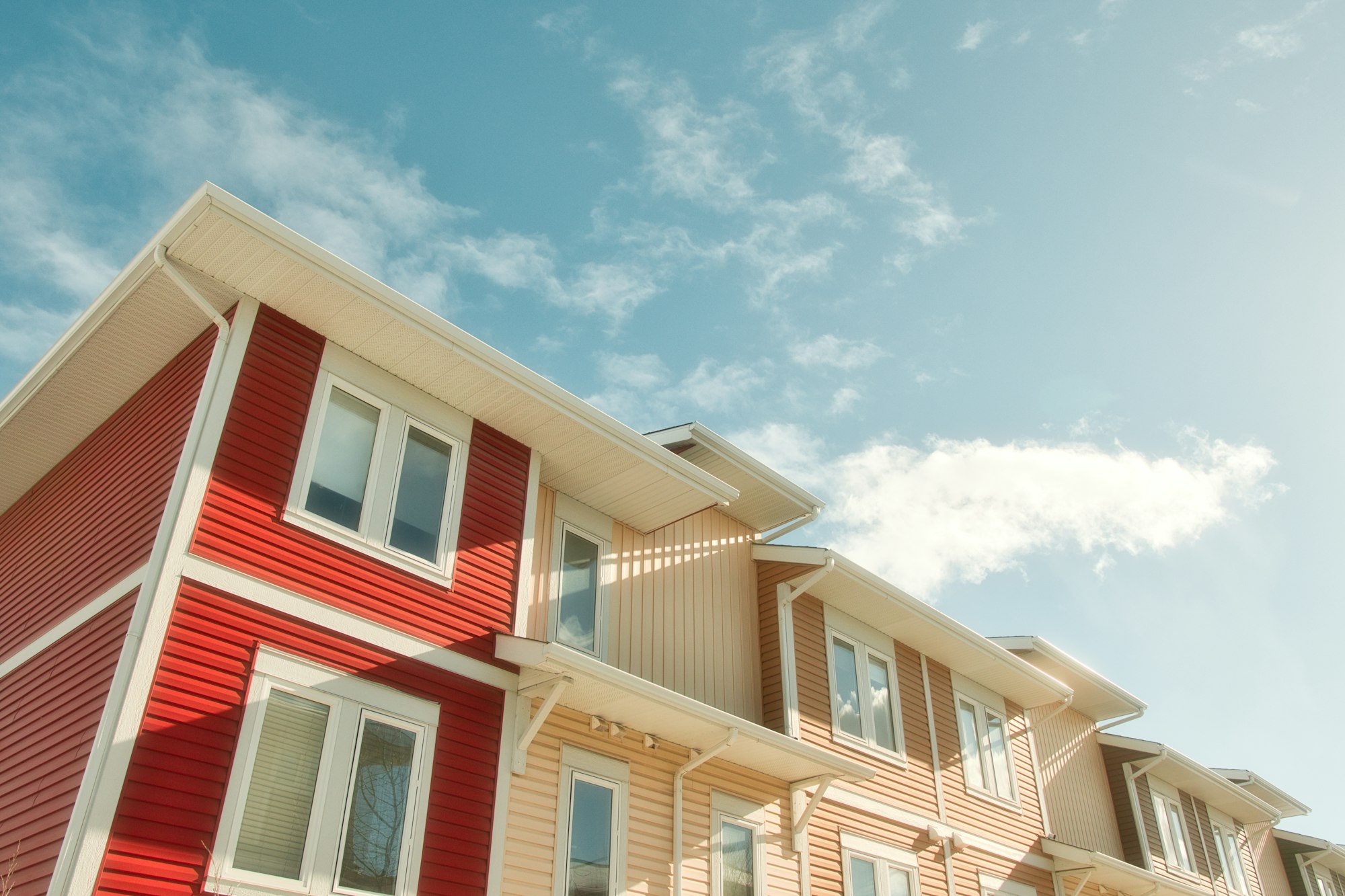 A row of multi-family townhouses under a blue sky