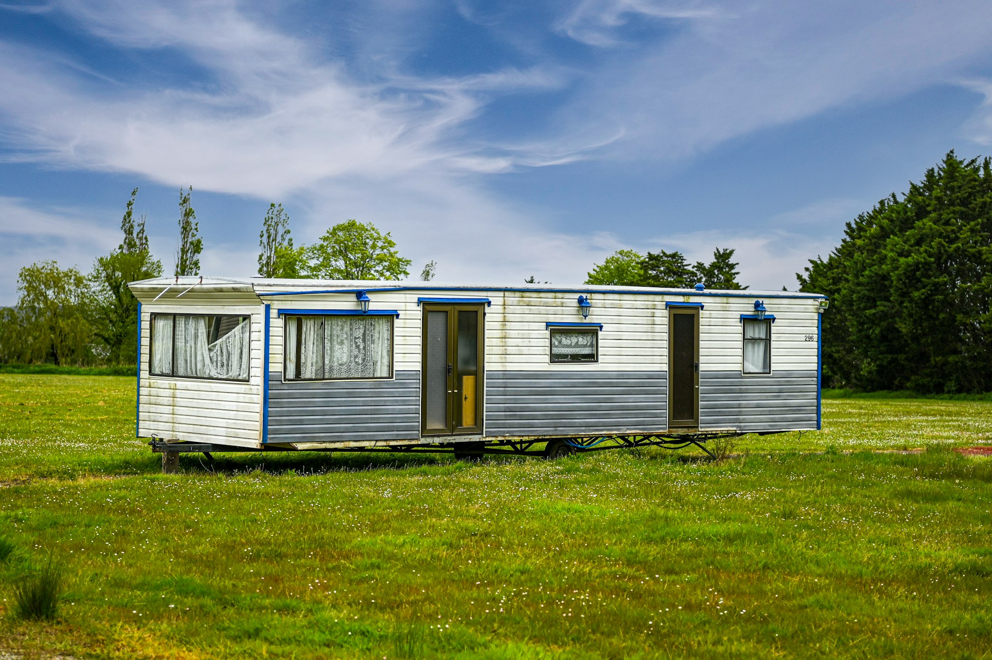 A mobile home set in an open grassy field