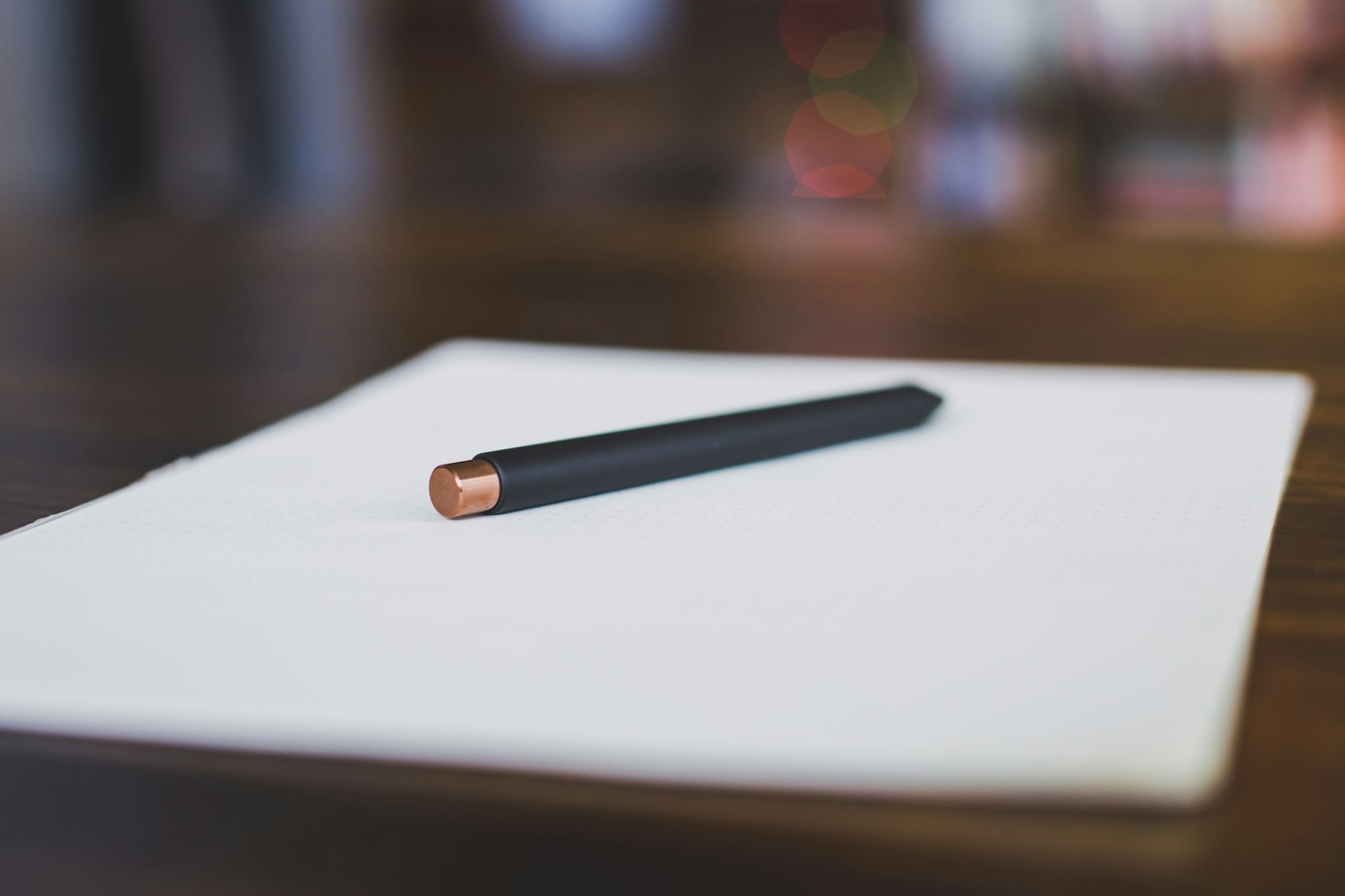 A pen resting on a blank notepad on a desk