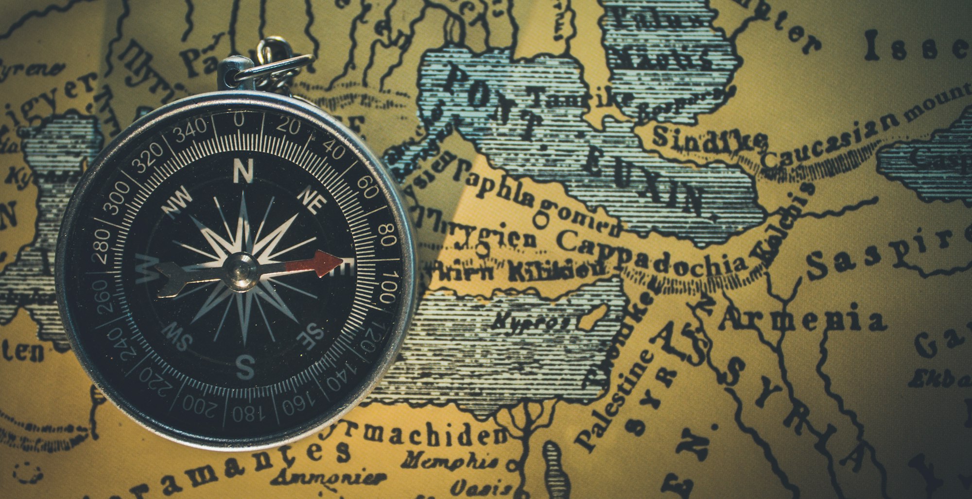 A vintage compass resting on an antique map