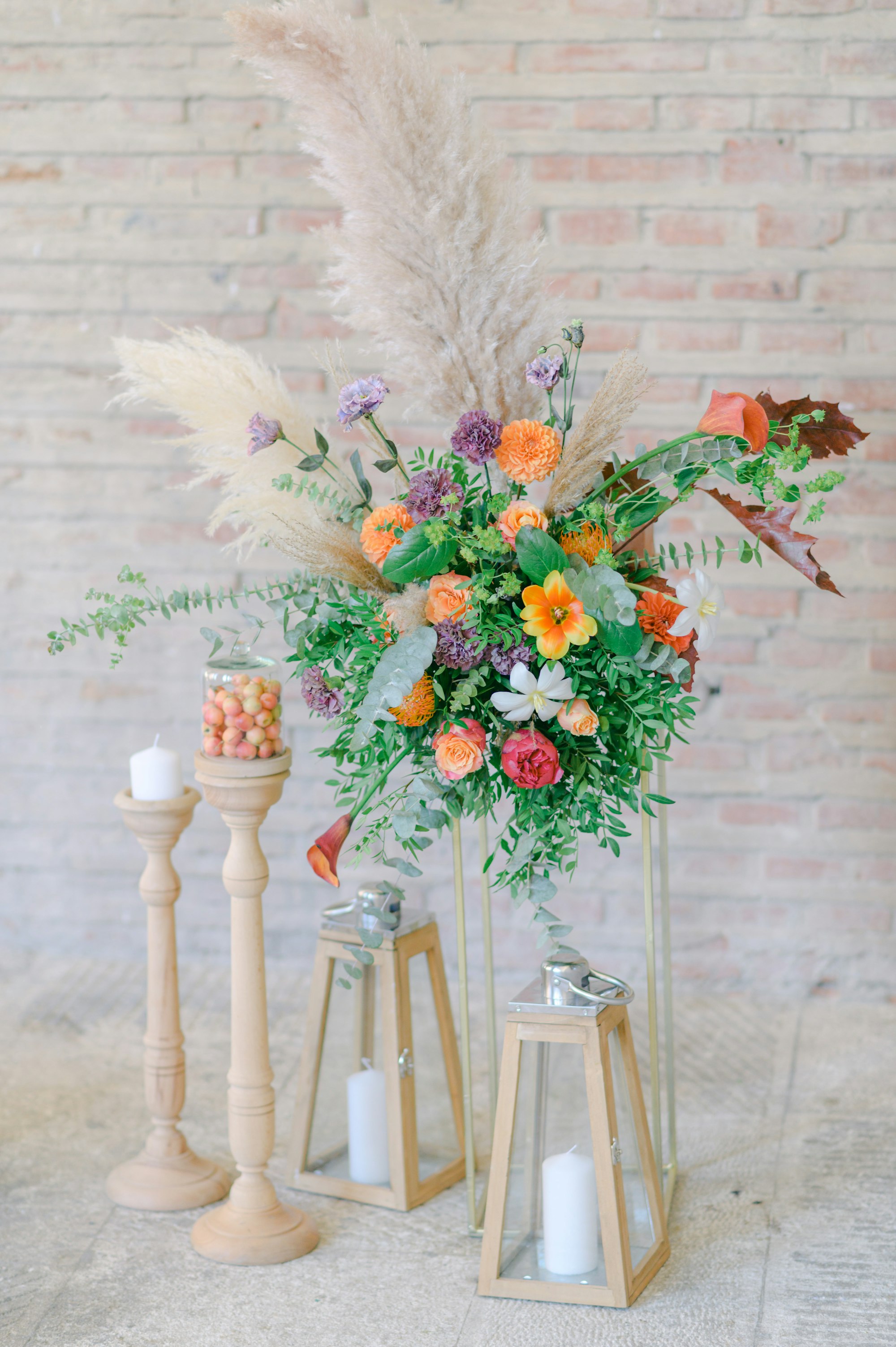 An elegant floral arrangement with pampas grass against a brick wall